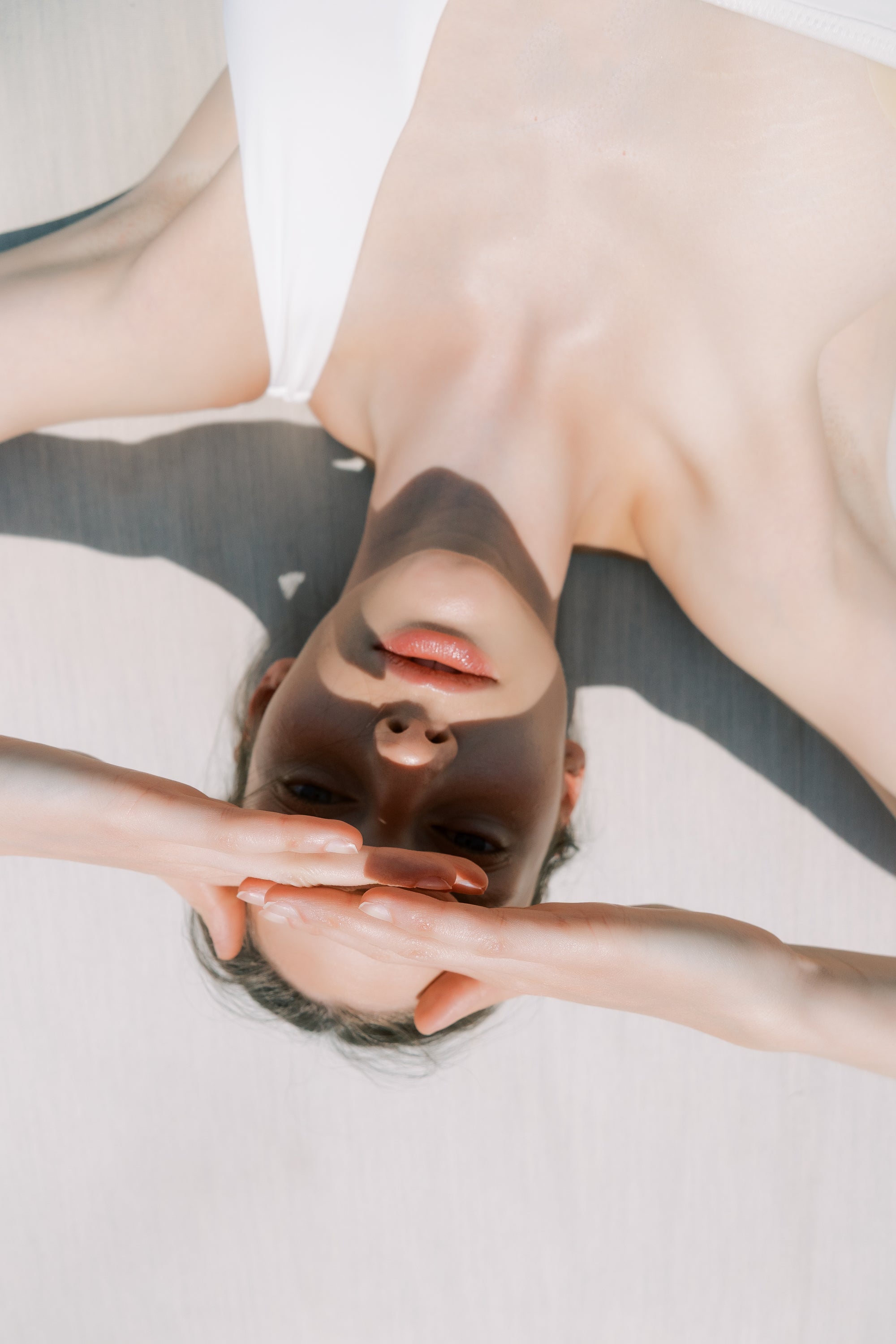 Person lying on a white surface with a neutral expression