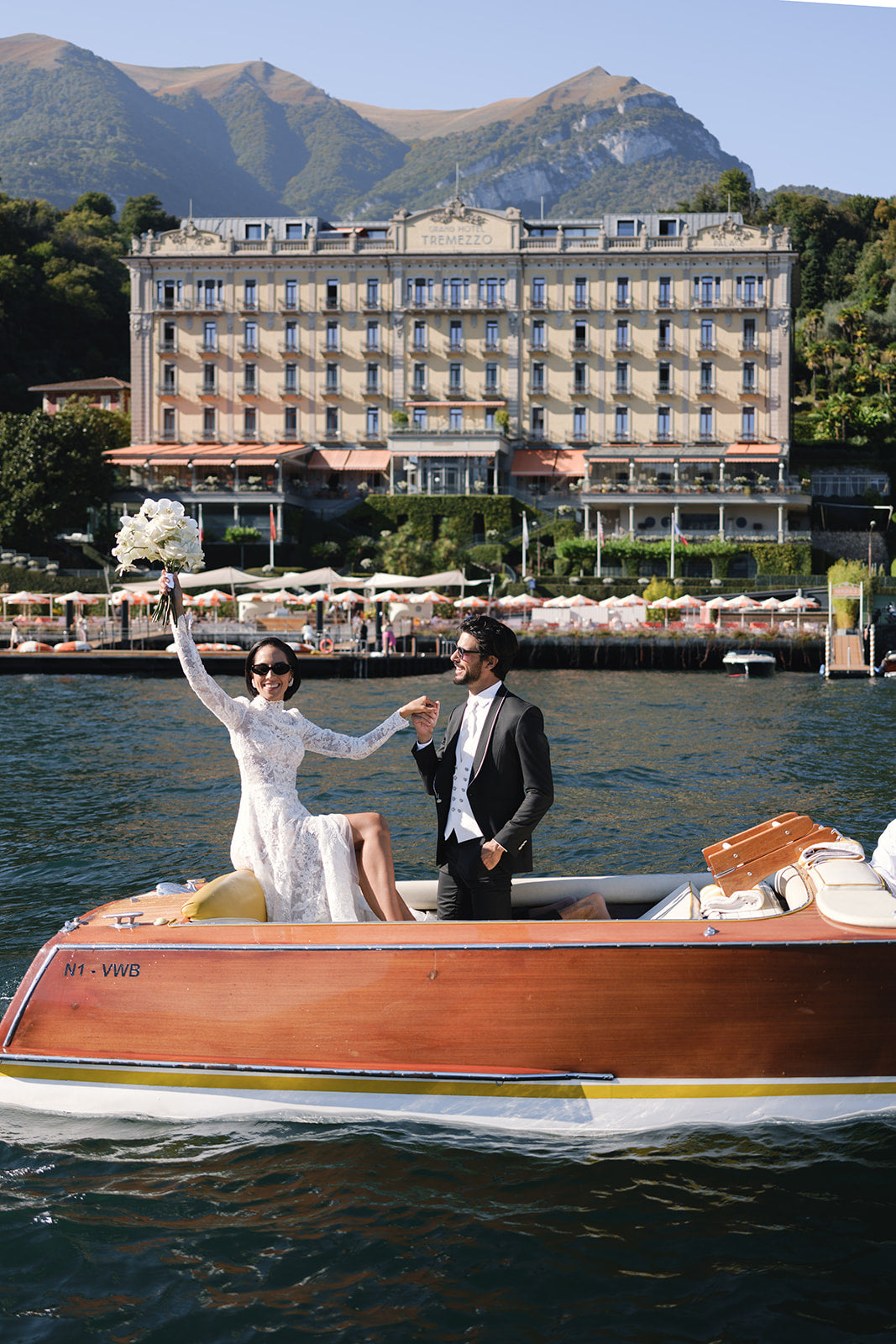 Two people in a boat on a lake with Grand hotel Tremezzo and mountains in the background