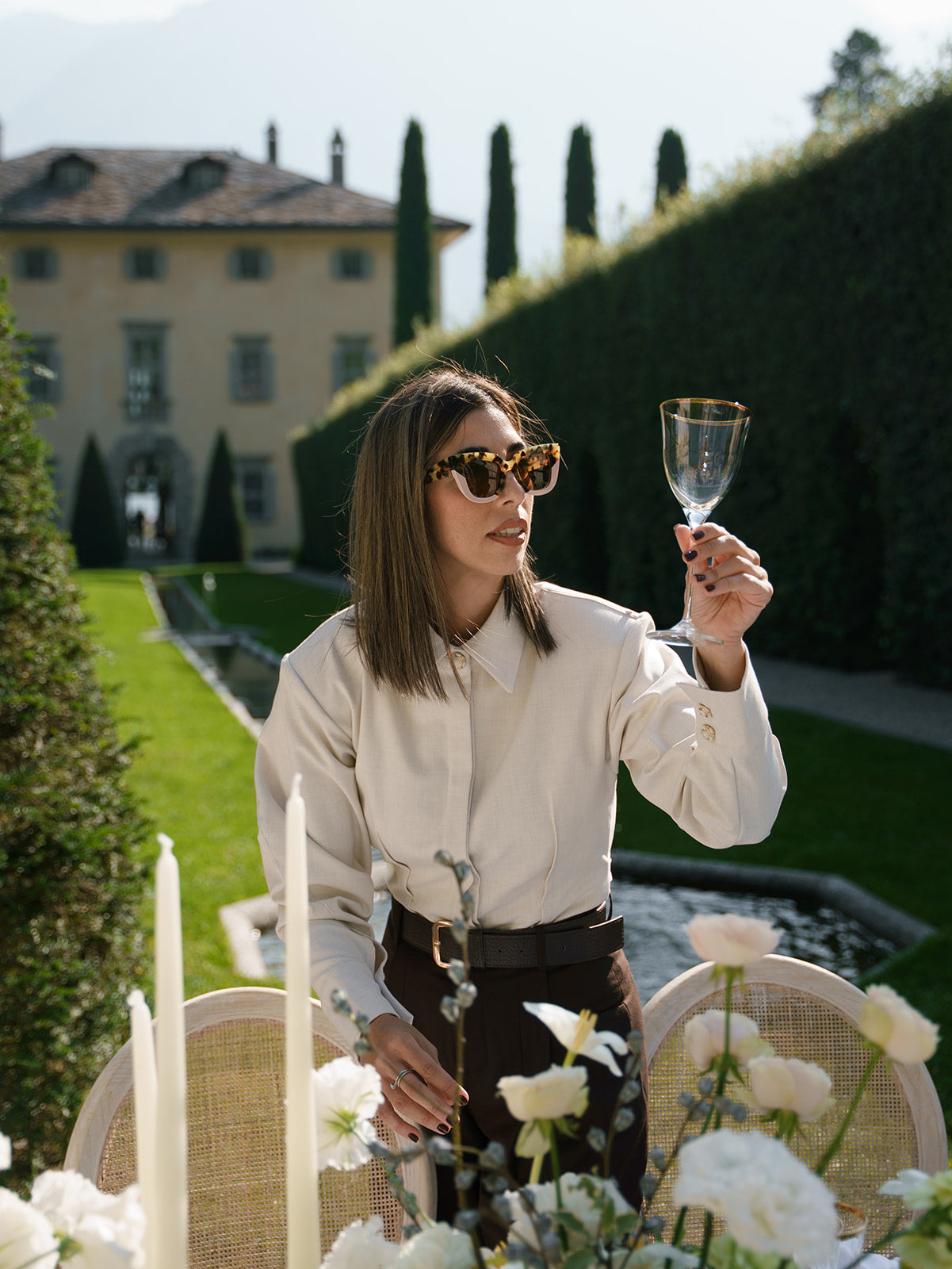 Planner holding a wine glass in an outdoor setting with villa Balbiano in the background